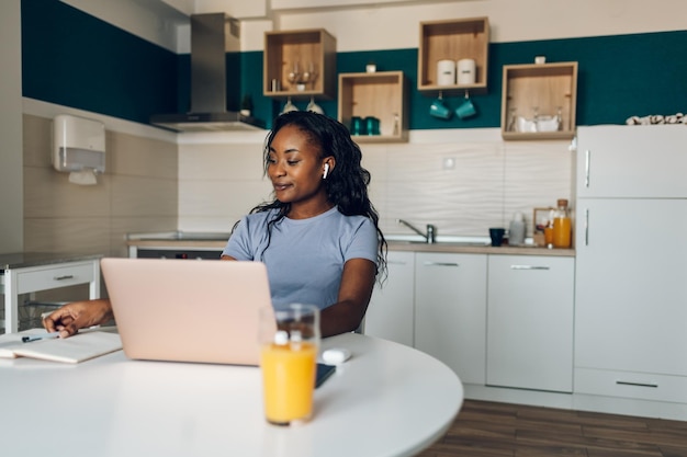 Jonge afro-amerikaanse vrouw die vanuit huis werkt en een laptop gebruikt