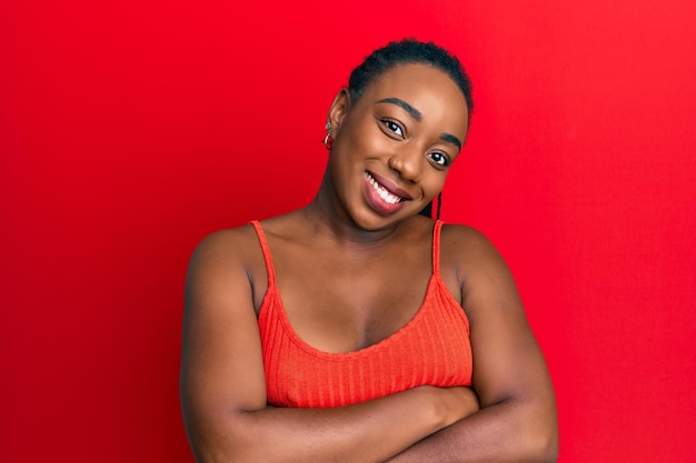Jonge afro-amerikaanse vrouw draagt casual stijl met mouwloos shirt blij gezicht lachend met gekruiste armen kijkend naar de positieve persoon van de camera