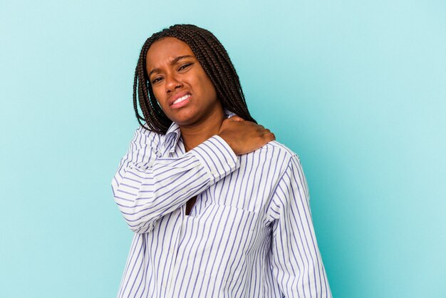 Jonge Afro-Amerikaanse vrouw geïsoleerd op blauwe achtergrond met pijn in de schouder.