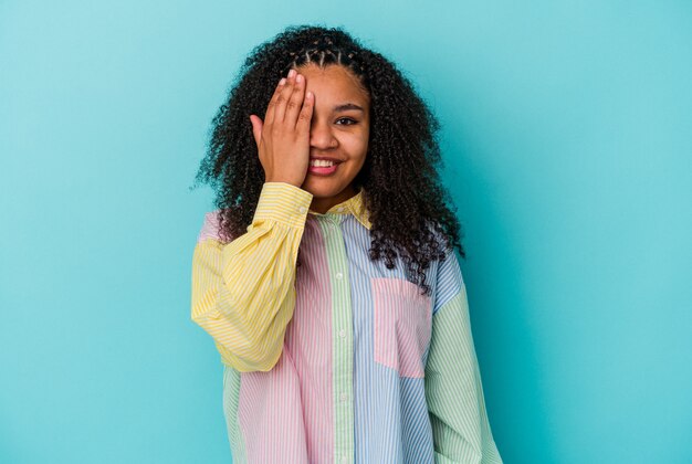 Jonge afro-amerikaanse vrouw geïsoleerd op blauwe achtergrond met plezier die de helft van het gezicht bedekt met palm.