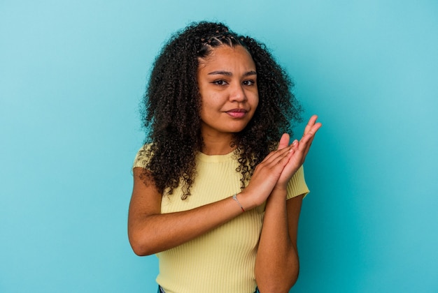 Jonge afro-amerikaanse vrouw geïsoleerd op een blauwe achtergrond die zich energiek en comfortabel voelt, zelfverzekerd handen wrijvend.