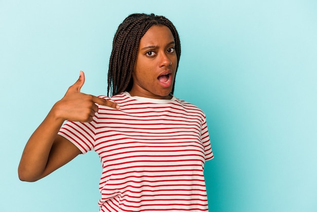 Jonge afro-amerikaanse vrouw geïsoleerd op een blauwe achtergrond persoon die met de hand wijst naar een shirt kopieerruimte, trots en zelfverzekerd