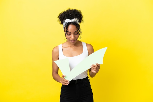 Jonge afro-amerikaanse vrouw geïsoleerd op een gele achtergrond met een vinkje en ernaar kijkend