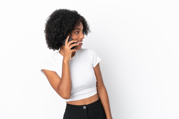 Jonge Afro-Amerikaanse vrouw geïsoleerd op een witte achtergrond die een gesprek houdt met de mobiele telefoon met iemand