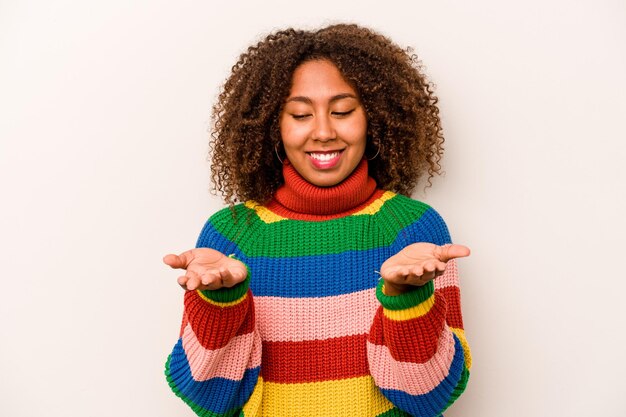 Jonge Afro-Amerikaanse vrouw geïsoleerd op een witte achtergrond die iets vasthoudt met handpalmen die aan de camera aanbieden