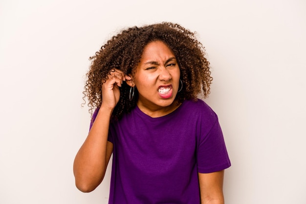 Jonge Afro-Amerikaanse vrouw geïsoleerd op een witte achtergrond die oren bedekt met vingers gestrest en wanhopig door een luid ambient