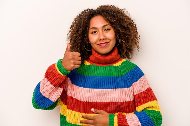 Jonge Afro-Amerikaanse vrouw geïsoleerd op een witte achtergrond raakt buik glimlacht zachtjes eten en tevredenheid concept