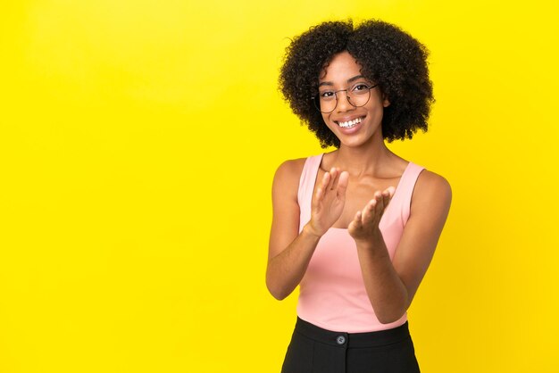 Jonge Afro-Amerikaanse vrouw geïsoleerd op gele achtergrond applaudisseren na presentatie in een conferentie