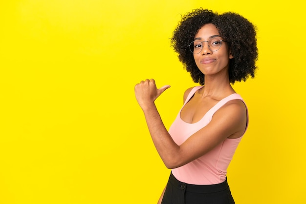 Jonge Afro-Amerikaanse vrouw geïsoleerd op gele achtergrond trots en zelfvoldaan