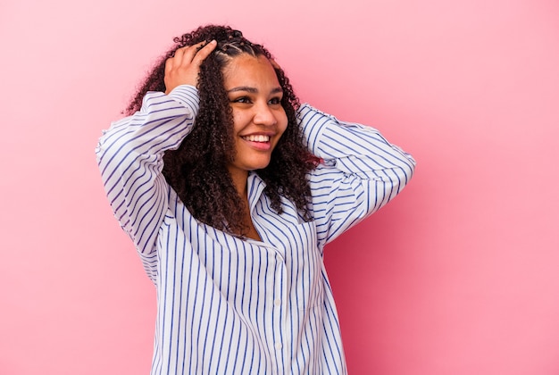 Jonge Afro-Amerikaanse vrouw geïsoleerd op roze achtergrond lacht vreugdevol handen op het hoofd houden. Geluk concept.