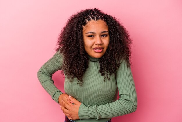 Jonge Afro-Amerikaanse vrouw geïsoleerd op roze achtergrond met een leverpijn, buikpijn.