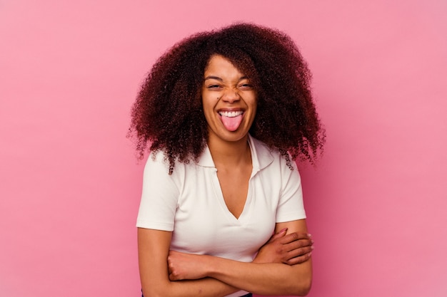 Jonge Afro-Amerikaanse vrouw geïsoleerd op roze grappige en vriendelijke tong uitsteekt.