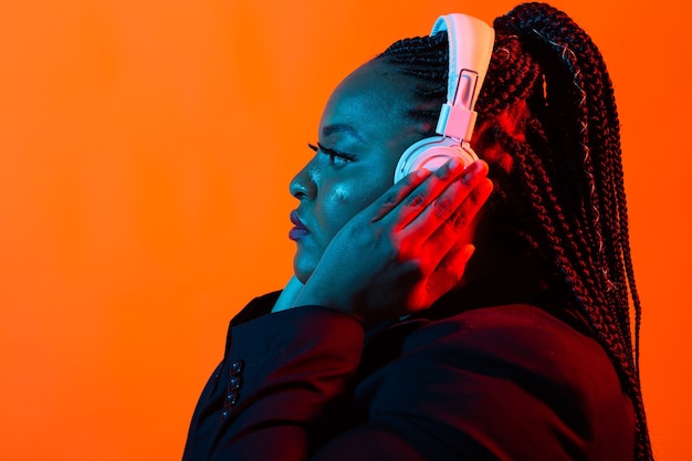 Jonge Afro-Amerikaanse vrouw luisteren naar muziek in koptelefoon in neonlicht. Vrouwelijk portret