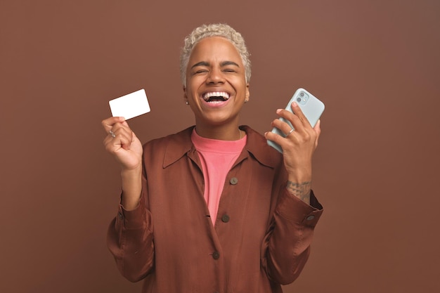 Jonge Afro-Amerikaanse vrouw met creditcard en telefoon geniet van online winkelen