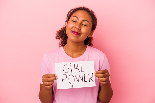 Jonge Afro-Amerikaanse vrouw met een girl power plakkaat geïsoleerd op roze background