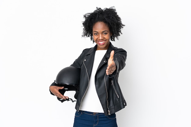 Jonge Afro-Amerikaanse vrouw met een motorhelm op witte muur handenschudden na een goede deal