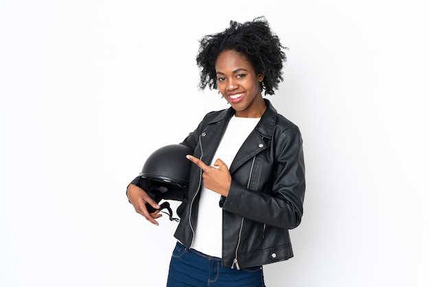 Jonge afro-amerikaanse vrouw met een motorhelm op witte muur wijzende vinger aan de zijkant