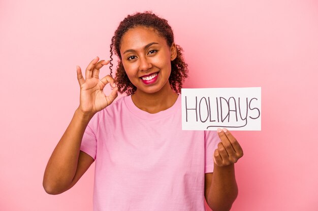 Jonge Afro-Amerikaanse vrouw met een vakantie plakkaat geïsoleerd op roze background