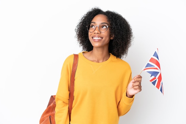 Jonge Afro-Amerikaanse vrouw met een vlag van het Verenigd Koninkrijk geïsoleerd op een witte achtergrond die een idee denkt terwijl ze omhoog kijkt