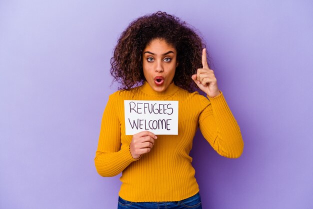 Jonge Afro-Amerikaanse vrouw met een vluchtelingen welkom bordje geïsoleerd met een idee, inspiratie concept.