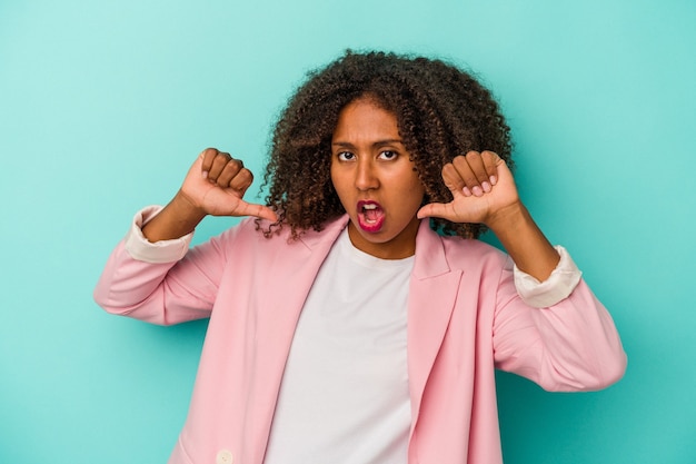 Jonge afro-amerikaanse vrouw met krullend haar geïsoleerd op blauwe achtergrond voelt zich trots en zelfverzekerd, voorbeeld om te volgen.