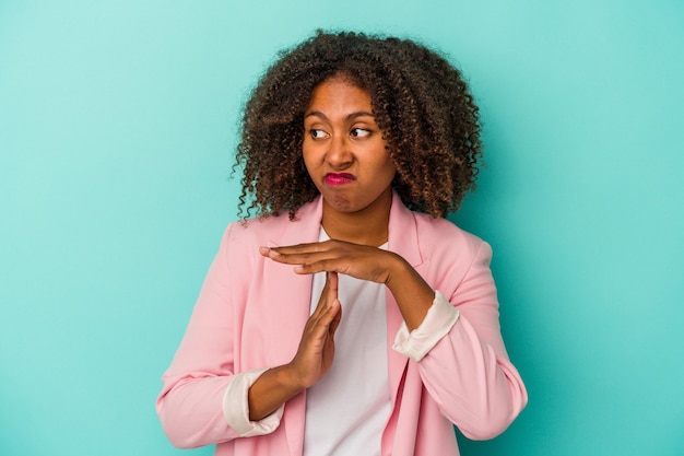 Jonge Afro-Amerikaanse vrouw met krullend haar geïsoleerd op een blauwe achtergrond met een time-outgebaar.