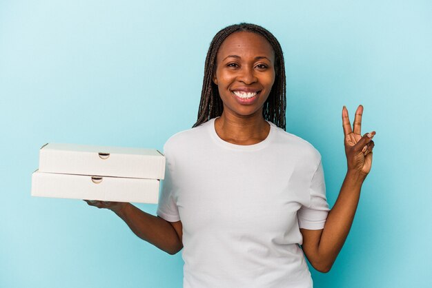 Jonge Afro-Amerikaanse vrouw met pizza's geïsoleerd op blauwe achtergrond met nummer twee met vingers.