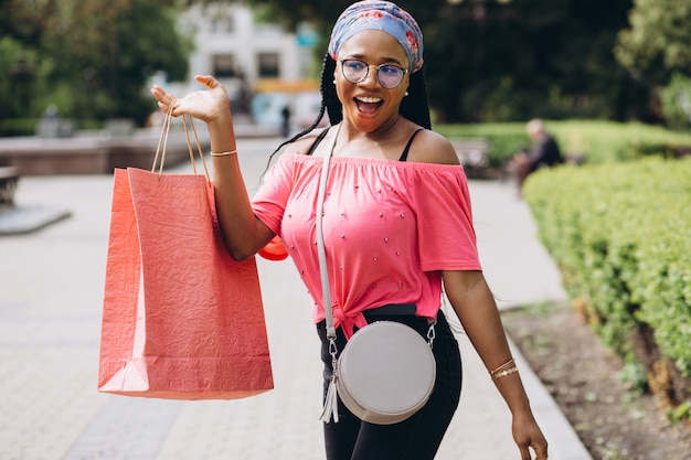 Jonge Afro-Amerikaanse vrouw op straat met boodschappentassen