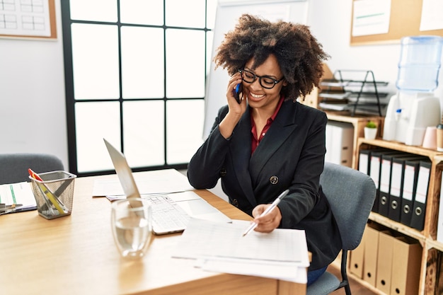 Jonge afro-amerikaanse vrouw praten op de smartphone werken op kantoor