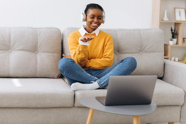 Jonge Afro-Amerikaanse vrouw praten over video-oproep in de woonkamer thuis afstandsonderwijs concept vanuit huis