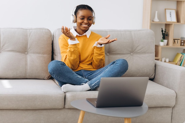 Jonge Afro-Amerikaanse vrouw praten over video-oproep in de woonkamer thuis afstandsonderwijs concept vanuit huis
