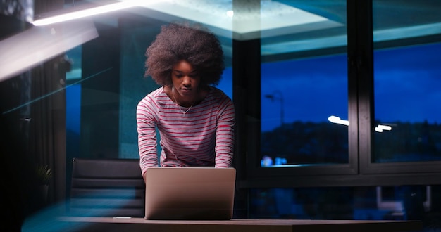 Jonge Afro-Amerikaanse vrouwelijke ondernemer freelancer werken met behulp van een laptop in de nacht Coworking-ruimte