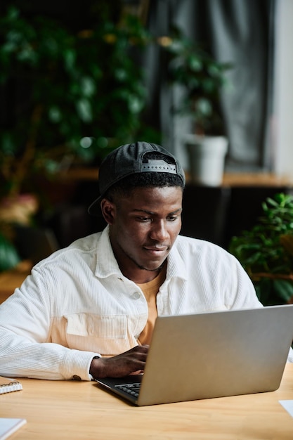 Jonge Afro-Amerikaanse zakenman die zich concentreert op het werk met online gegevens