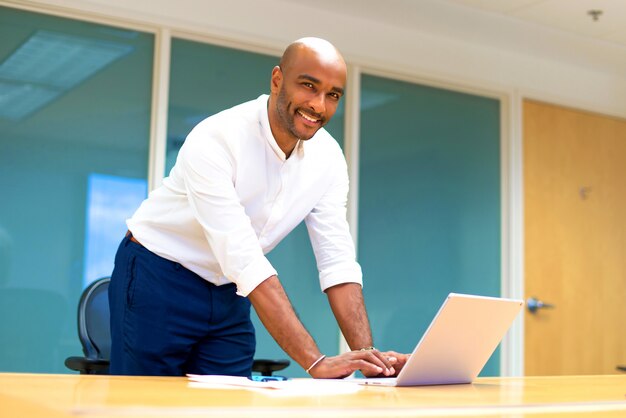 Jonge Afro-Amerikaanse zakenman in het kantoor met zijn laptop