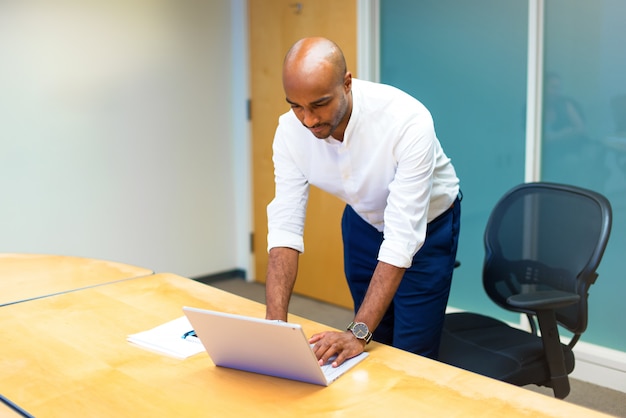 Jonge Afro-Amerikaanse zakenman in het kantoor met zijn laptop