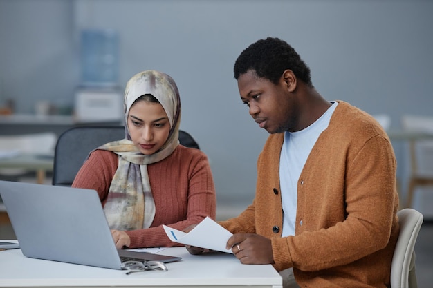 Jonge Afro-Amerikaanse zakenman met document laptop scherm kijken