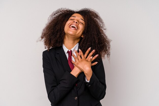 Jonge afro-amerikaanse zakenvrouw, gekleed in een pak dat op een witte achtergrond wordt geïsoleerd, lacht terwijl ze de handen op het hart houdt, concept van geluk.