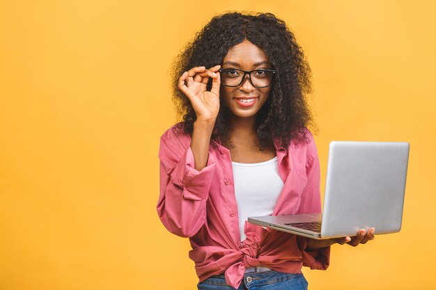 Jonge Afro-Amerikaanse zwarte positieve coole dame met krullend haar met behulp van laptop en glimlachen