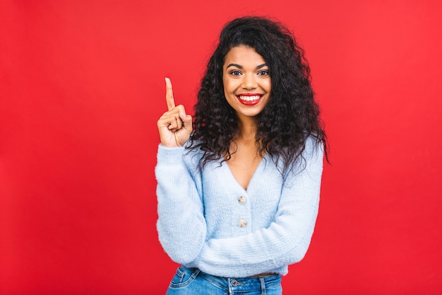 jonge Afro-Amerikaanse zwarte vrouw die omhoog geïsoleerd op rode achtergrond