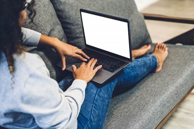 Jonge Afro-Amerikaanse zwarte vrouw ontspannen en het gebruik van laptopcomputer met witte mockup lege schermen. Vrouw sociale apps en werken controleren. Communicatie en technologie concept