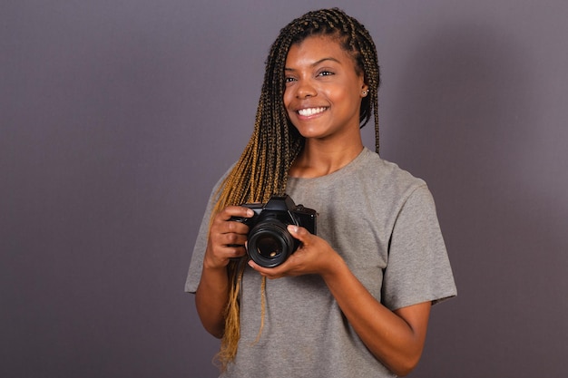 Jonge Afro-Braziliaanse vrouw fotograaf glimlachend met fotocamera