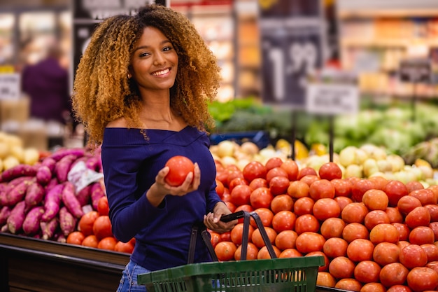 Jonge afro die tomaten op de markt selecteert