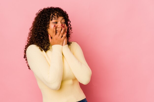 Jonge afro geïsoleerde vrouw lachend over iets, mond bedekt met handen