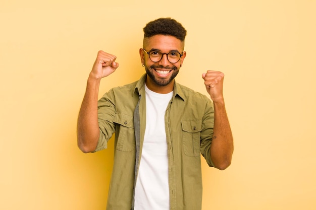 Jonge afro-man die blij verrast en trots schreeuwt en succes viert met een grote glimlach