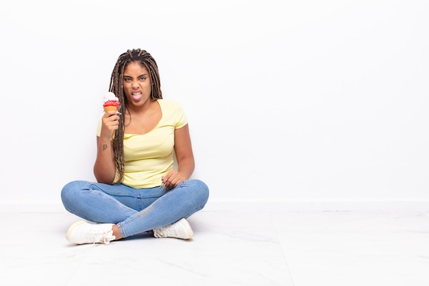 Jonge afro-vrouw die walgt en geïrriteerd voelt, tong uitsteekt, niet van iets smerigs en vies houdt.