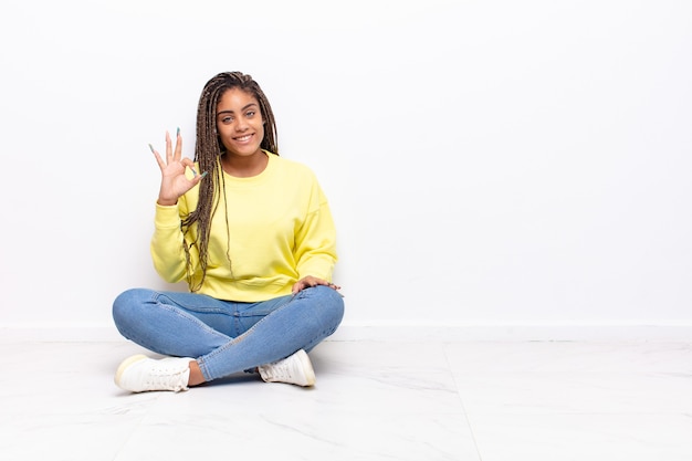 jonge afro-vrouw die zich gelukkig, ontspannen en tevreden voelt, goedkeuring toont met een goed gebaar, glimlachend