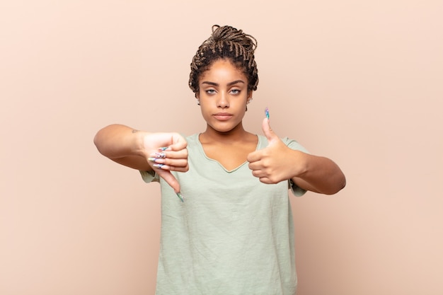 Jonge afro-vrouw die zich verward, geen idee en onzeker voelt, het goede en slechte afwegen in verschillende opties of keuzes