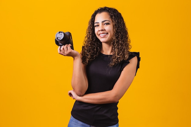 Jonge afro vrouw fotografie op gele achtergrond met een fotocamera.