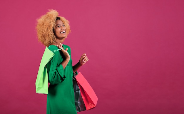 Jonge afro-vrouw houdt boodschappentassen vast terwijl ze op een geïsoleerde achtergrond staat. Black Friday seizoen verkoop concept.