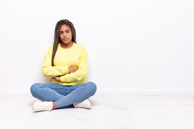 Jonge afrovrouw die zich ontevreden en teleurgesteld voelt, ernstig, geïrriteerd en boos kijkt met gekruiste armen